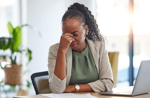 Woman experiencing headache pain while working in an office