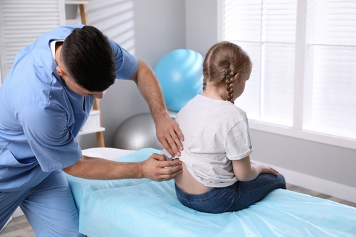 Child receiving spinal assessment from chiropractor. Chiropractor evaluating a child's spine.